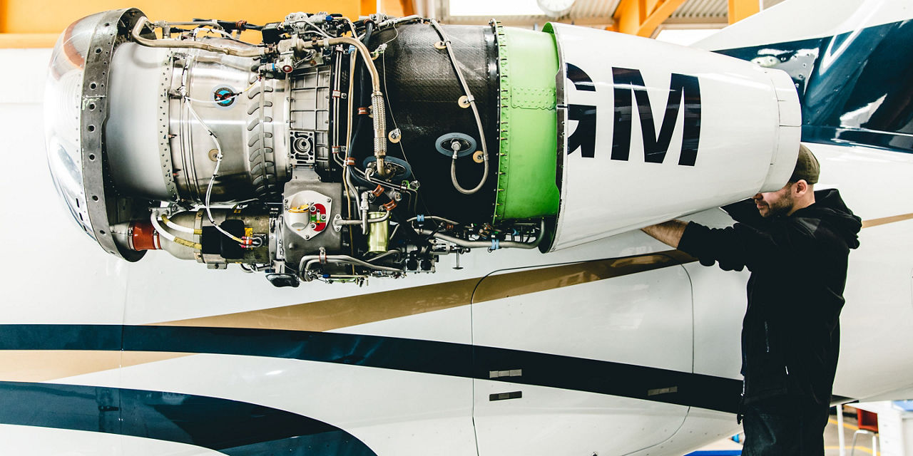 Engineer works at the jet engine of an airplane, inside hangar