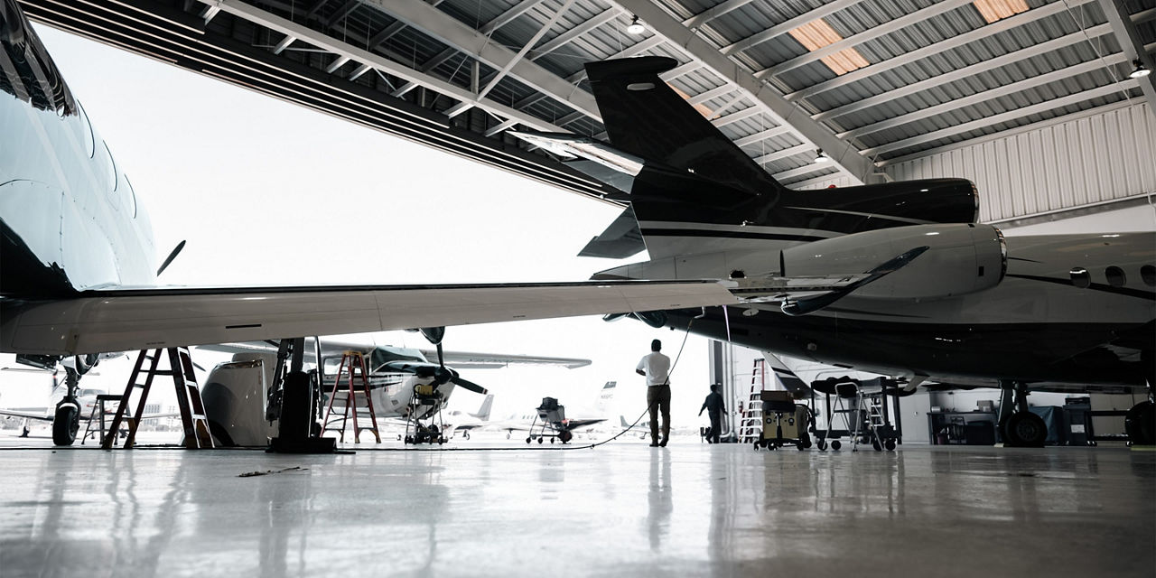 Maintenance being performed on private jet in a hangar.