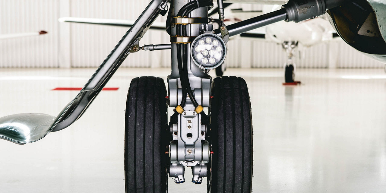 Close-up of landing gear equipped with a landing light, shot inside a brightly-lit hangar