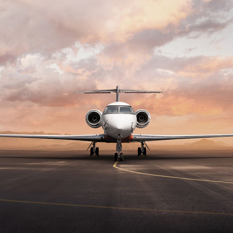 Private business jet parked on runway at sunset