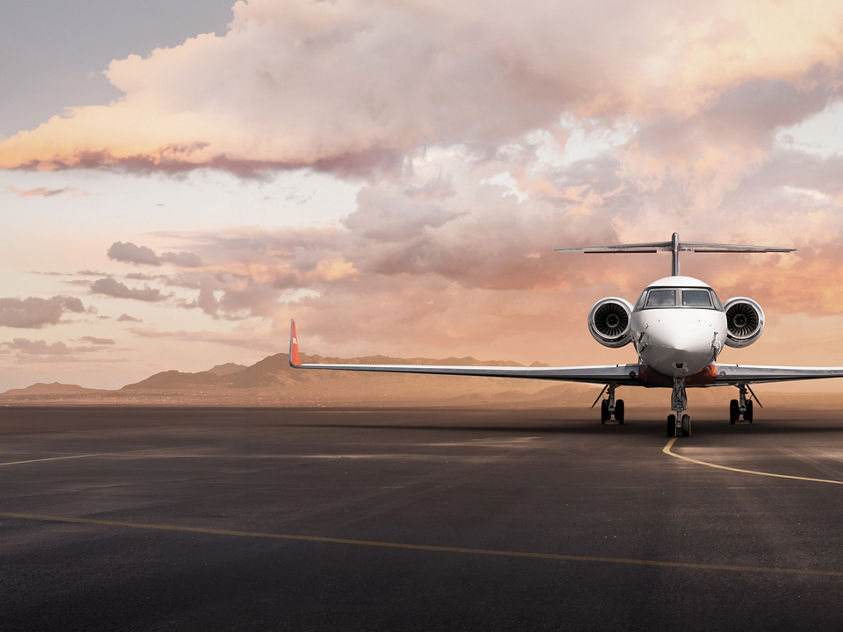 Private business jet parked on runway at sunset