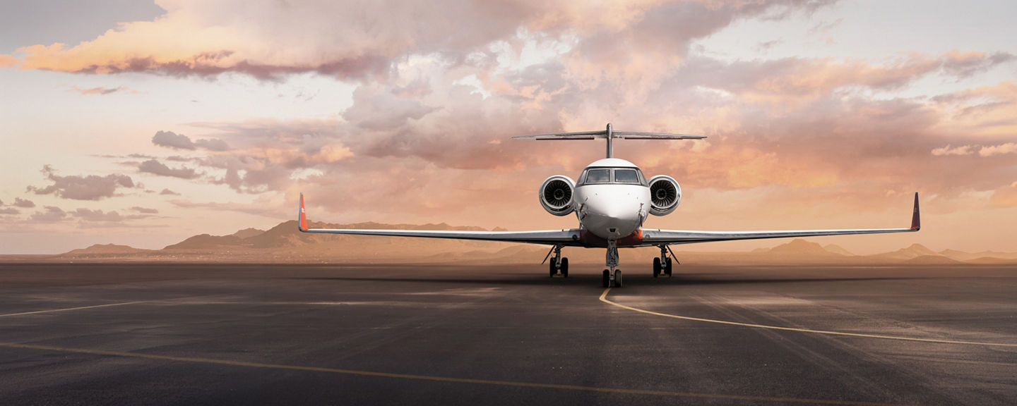 Private business jet parked on runway at sunset