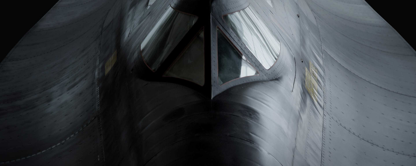 Dramatic frontal view of a military aircraft emphasizing cockpit geometry, metallic surfaces, and stealth-oriented design.