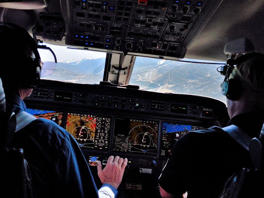 This image depicts a flight crew in the cockpit of a Honeywell RNPFMS-equipped aircraft during a navigation approach. 
