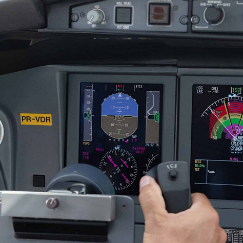 Commercial pilot holding flight control system inside modern airplane cockpit.