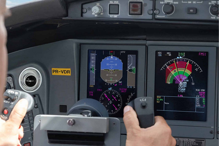 Commercial pilot holding flight control system inside modern airplane cockpit.