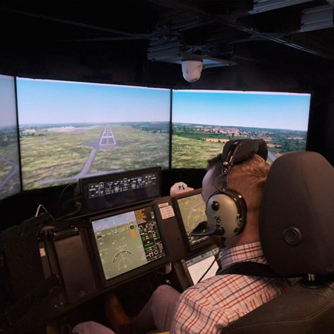 Two people using a sophisticated flight simulator that mimics a modern cockpit environment