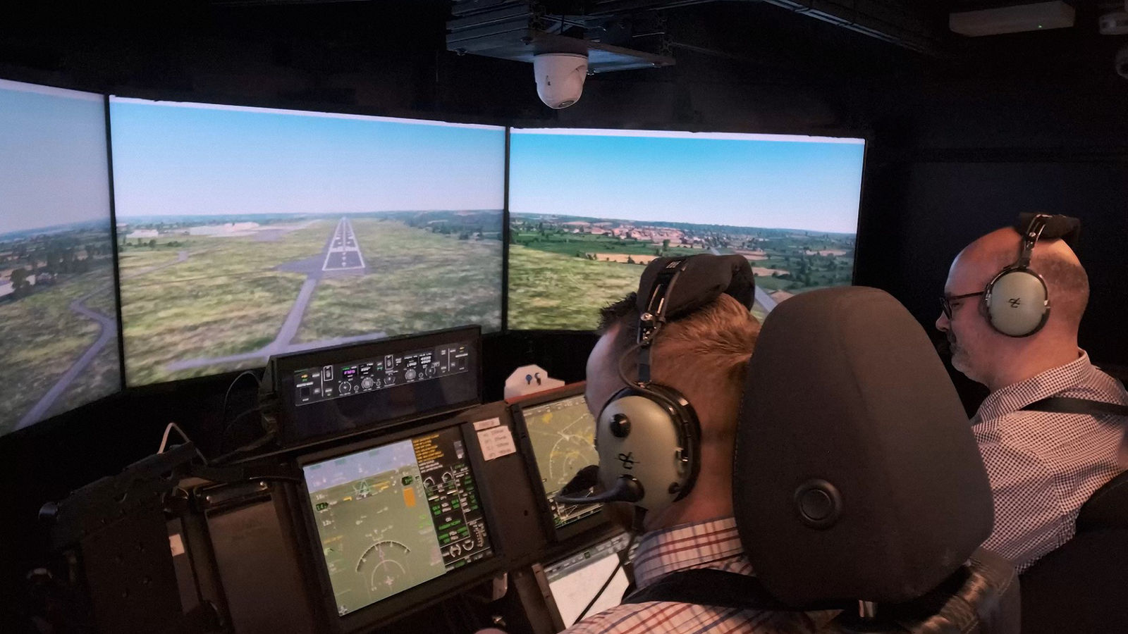Two people using a sophisticated flight simulator that mimics a modern cockpit environment