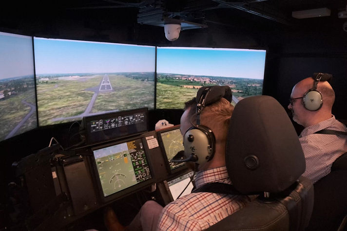 Two people using a sophisticated flight simulator that mimics a modern cockpit environment