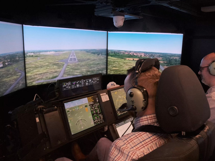 Two people using a sophisticated flight simulator that mimics a modern cockpit environment