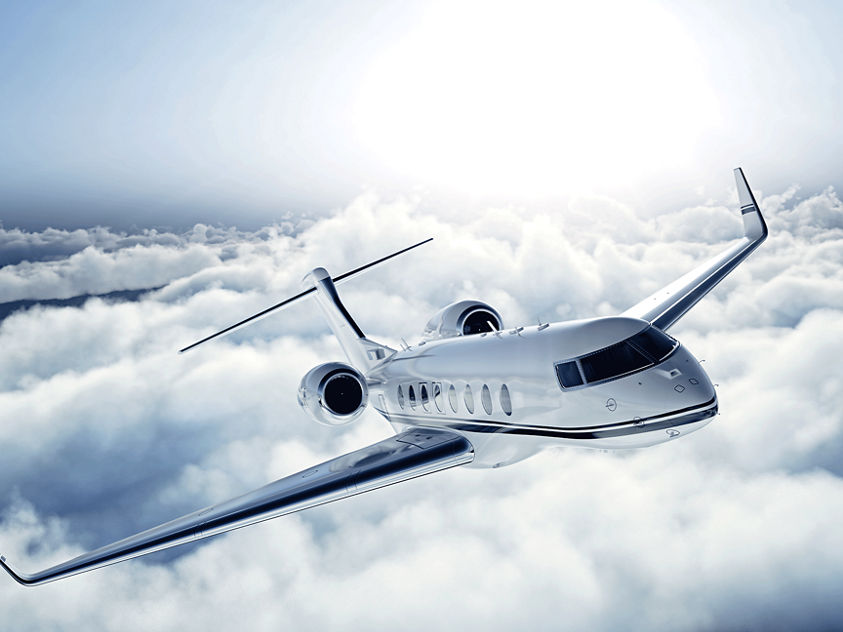 image of a business jet flying over the clouds 