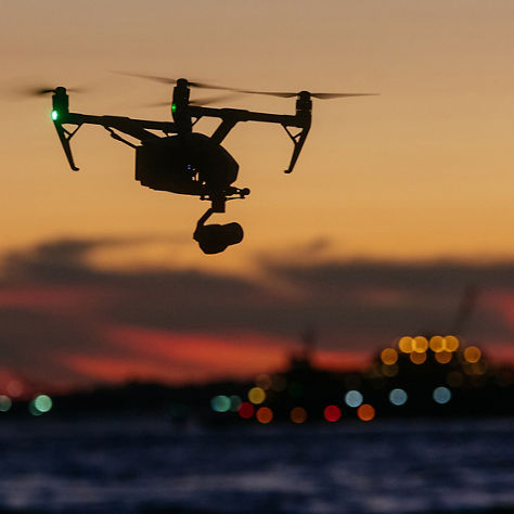 A professional drone captures stunning sunset views over water, showcasing modern aerial videography and scenic evening light.