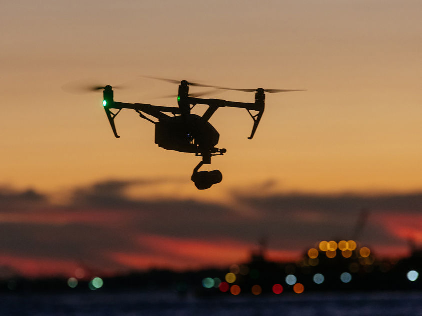 A professional drone captures stunning sunset views over water, showcasing modern aerial videography and scenic evening light.