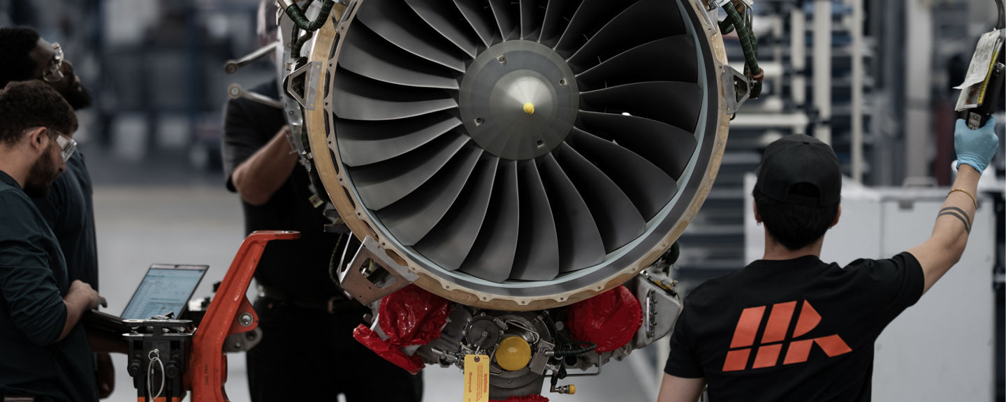 Group working around exposed turbine with visible fan blades, emphasizing scale, teamwork and technical detail.