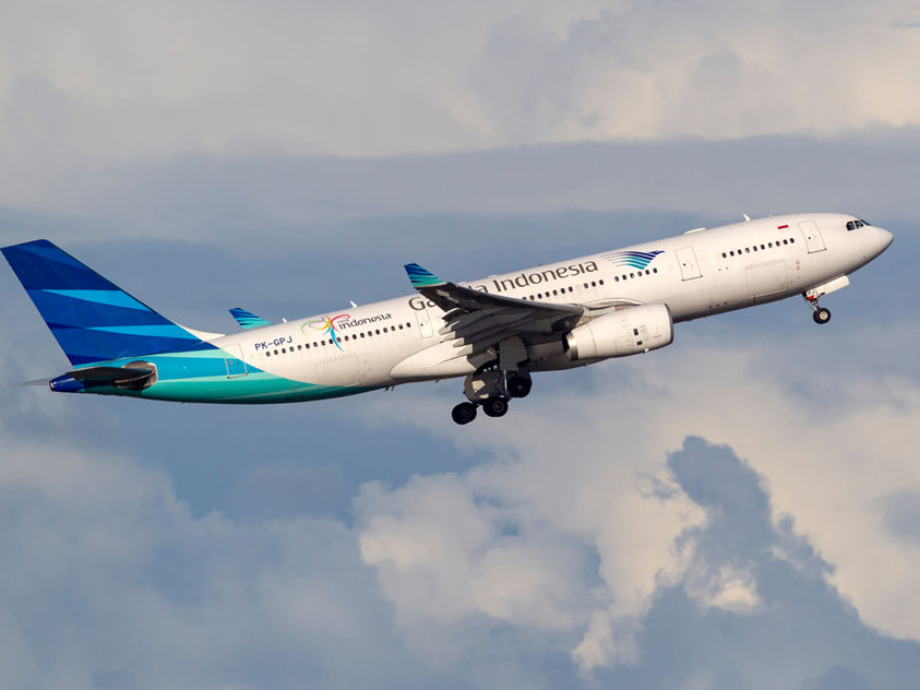 A Garuda Indonesia aircraft with blue tail design captured mid-flight, highlighting aviation and airline branding.