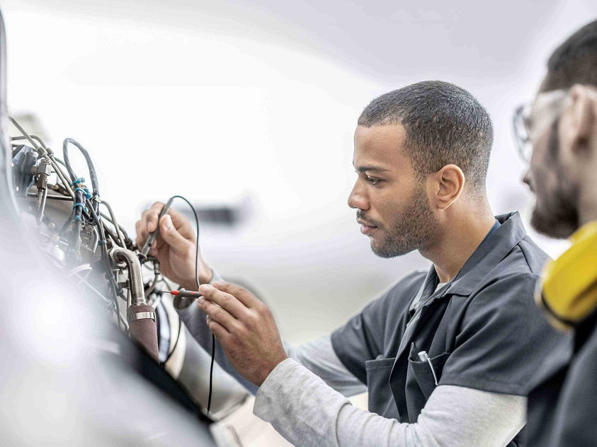 Maintenance professional testing avionics connections inside an aircraft service environment.