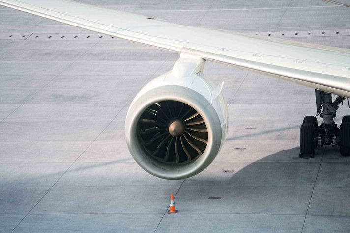 Close-up of a turbofan engine mounted under a wing with safety cone positioned on the apron.