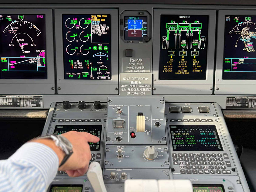 Inside a cockpit, a man operates a plane, focused on various screens that show essential flight information.