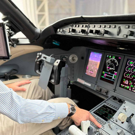 A man seated in the cockpit of an airplane, focused on the controls and instruments in front of him.
