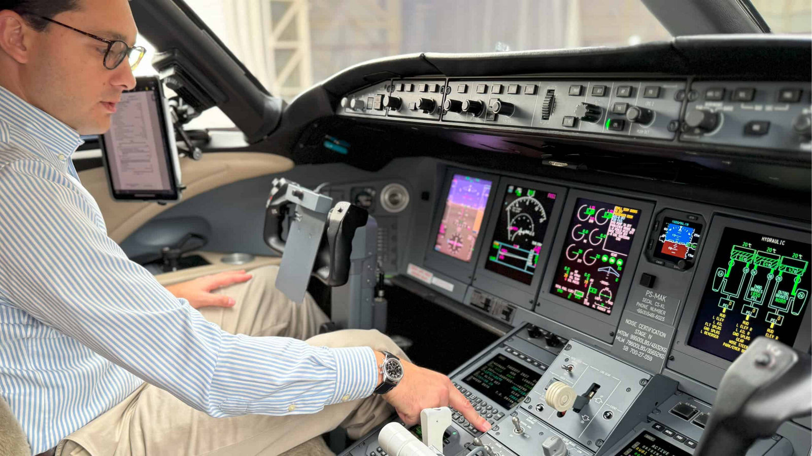 A man seated in the cockpit of an airplane, focused on the controls and instruments in front of him.