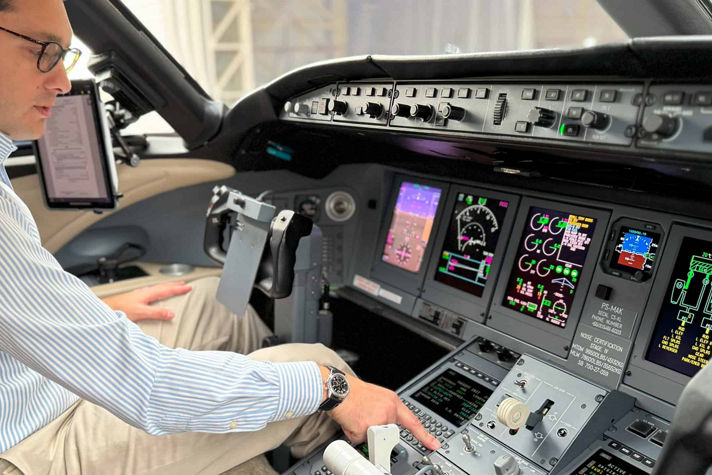 A man seated in the cockpit of an airplane, focused on the controls and instruments in front of him.