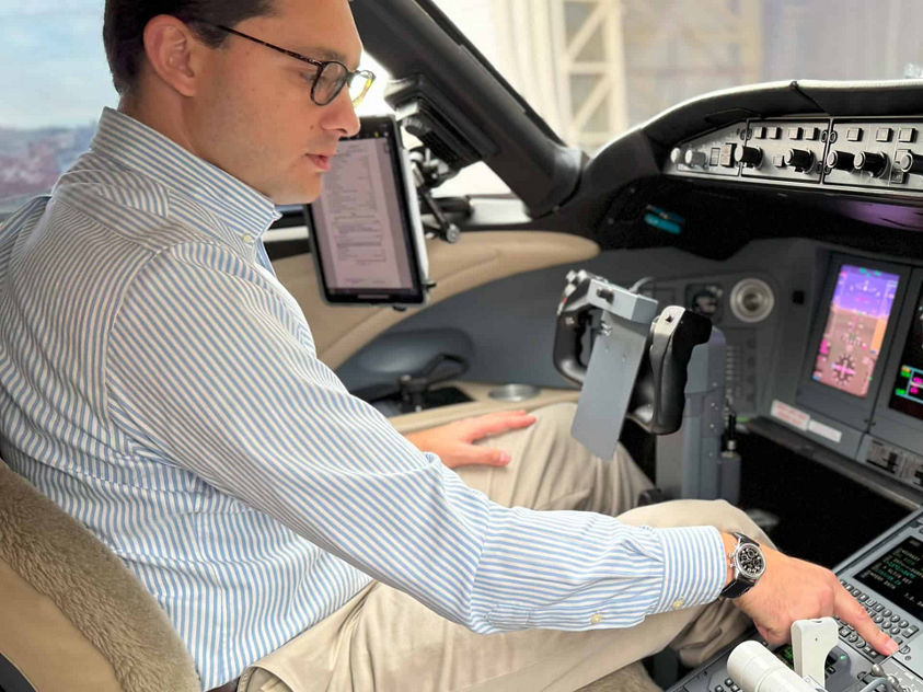 A man seated in the cockpit of an airplane, focused on the controls and instruments in front of him.