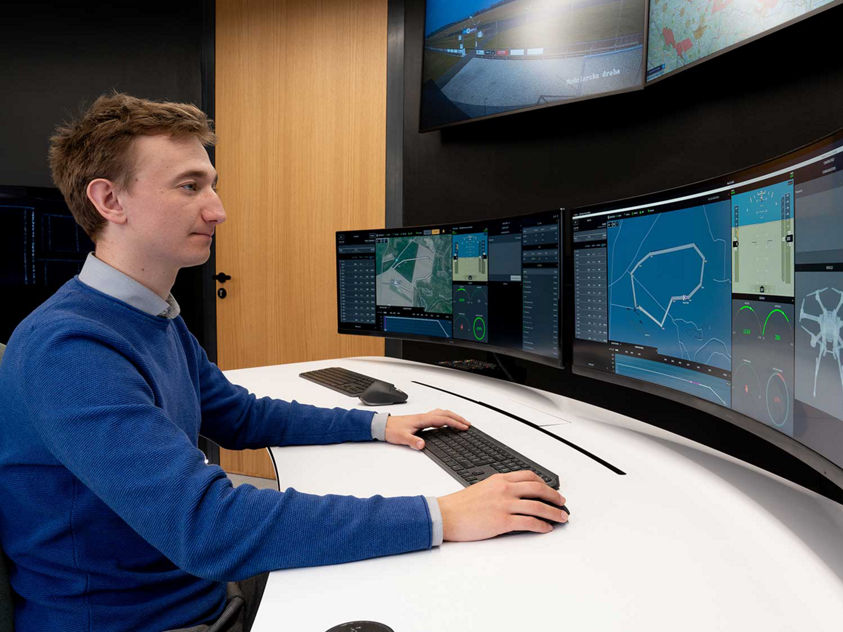 Person analyzing data on curved monitors in control center.