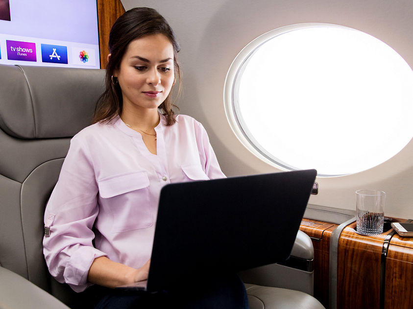 In-flight workspace with laptop, drink, and entertainment
