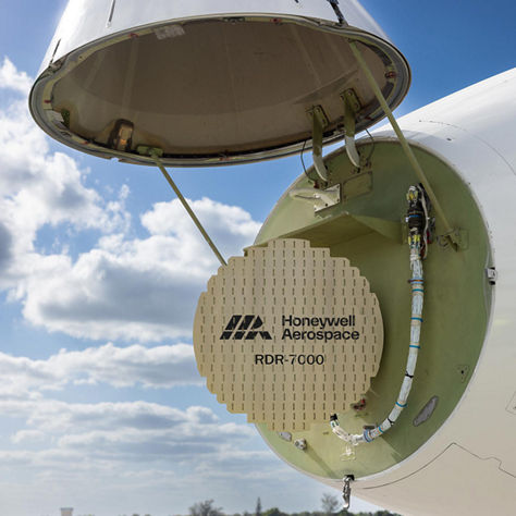 An aircraft’s nose compartment is open, revealing the Honeywell Aerospace RDR‑7000 radar system against a bright sky. The image highlights advanced radar technology and aircraft maintenance access.