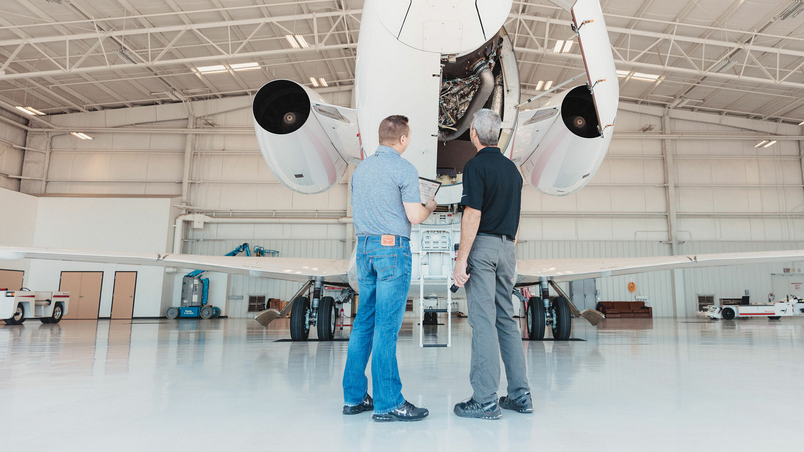 image of two men examine the engine of a private jet while standing in front of it.