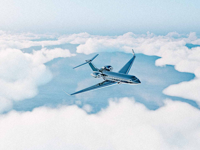 The image shows a business jet flying above the clouds. 