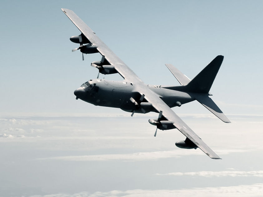 Military cargo aircraft flying over a cloud-covered sky