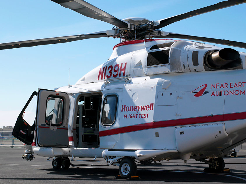 White and red helicopter labeled Honeywell Flight Test and Near Earth Autonomy, parked with door open on airport tarmac.