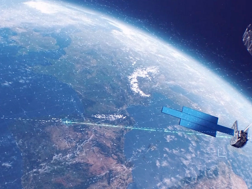 A satellite with blue solar panels and antenna orbits Earth, showing clouds, landmasses, and oceans below.