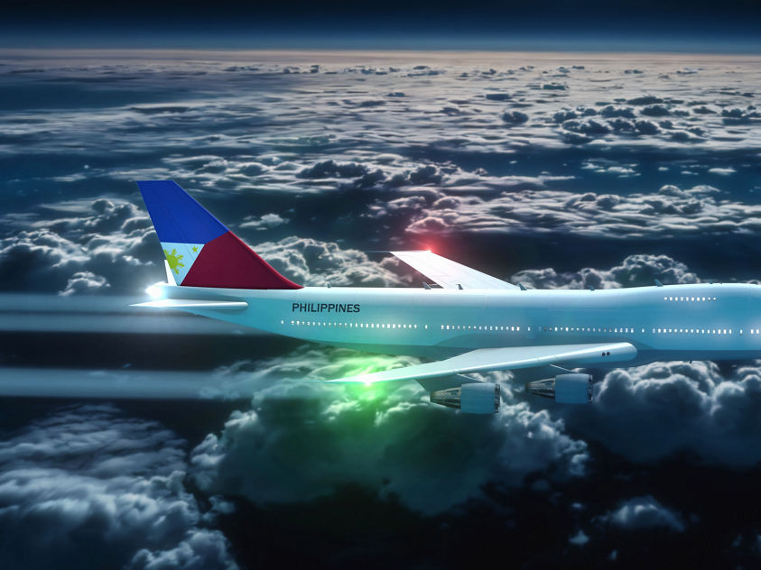 An aircraft bearing Philippine markings soars above the clouds during twilight conditions.
