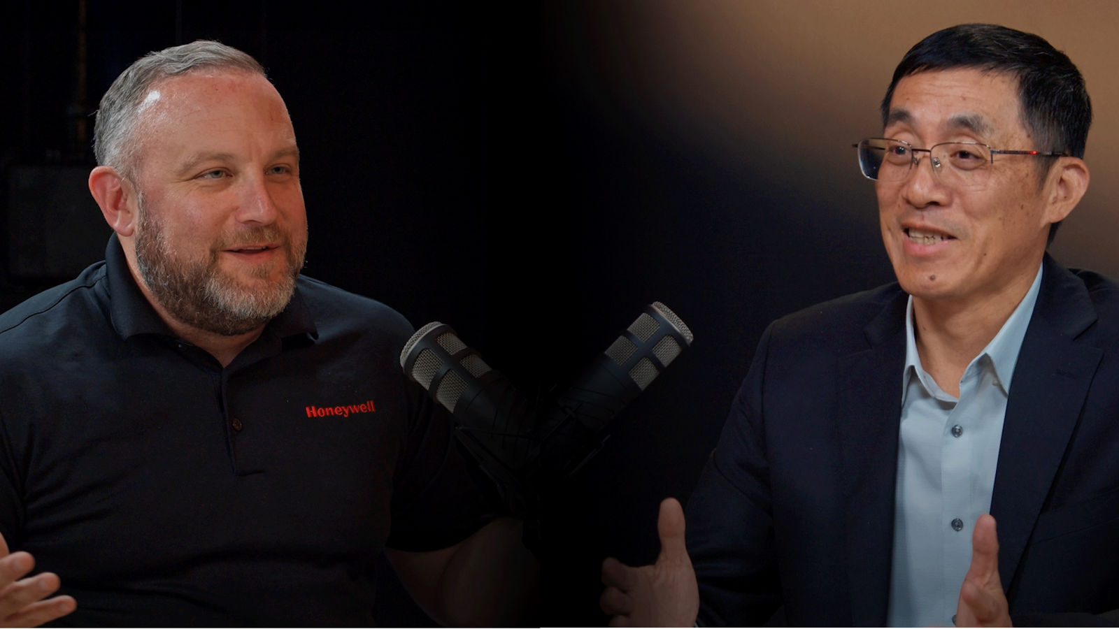 Two individuals discuss industry topics in a formal setting, featuring a Honeywell-branded participant and microphones.