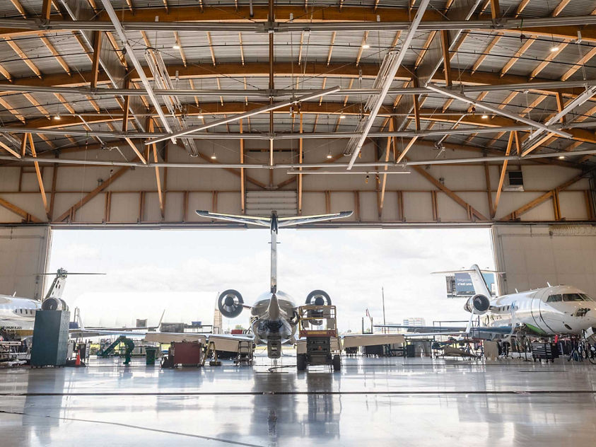 A spacious hangar filled with multiple airplanes parked inside, showcasing various aircraft models.
