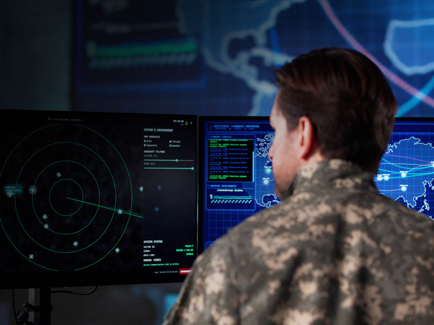a soldier in a military command or control center, actively engaged in monitoring computer systems