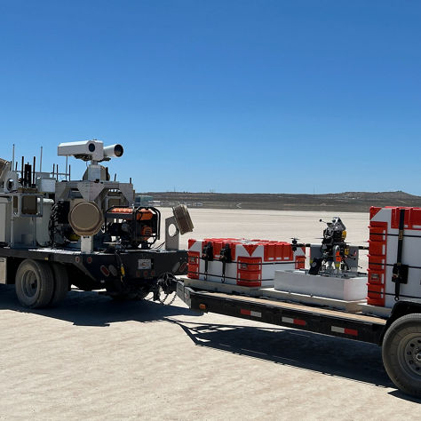 A Honeywell-branded truck equipped with scientific instruments and trailer containers in a wide-open field setting.