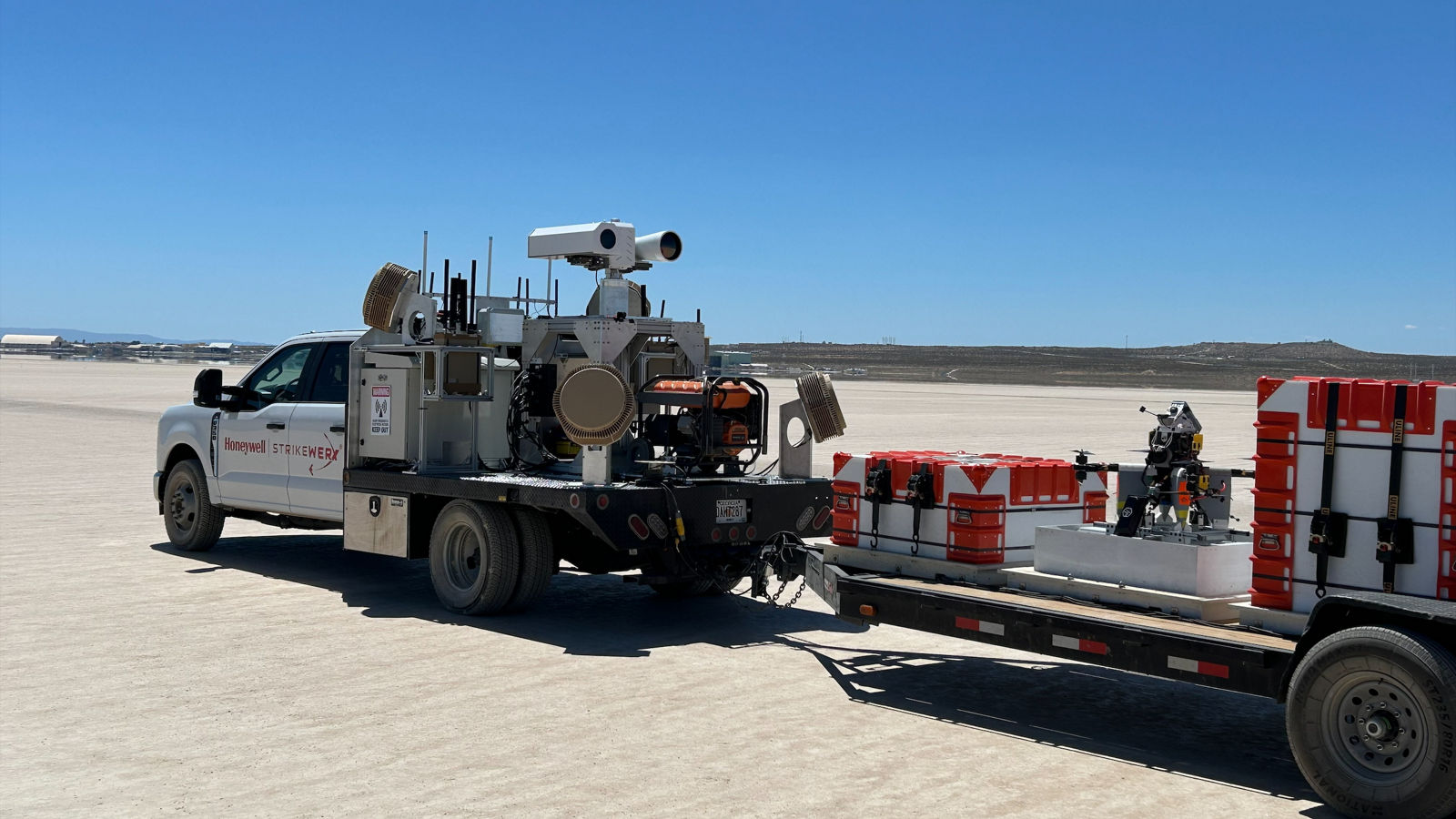 A Honeywell-branded truck equipped with scientific instruments and trailer containers in a wide-open field setting.