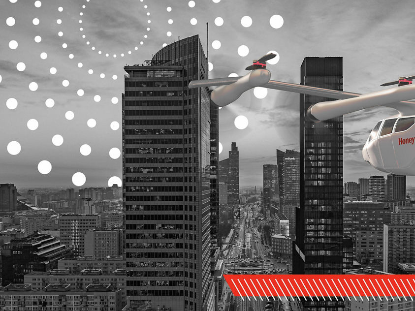 A red and white Honeywell-branded flying vehicle navigates a grayscale cityscape of towering skyscrapers, highlighting advanced urban air mobility.