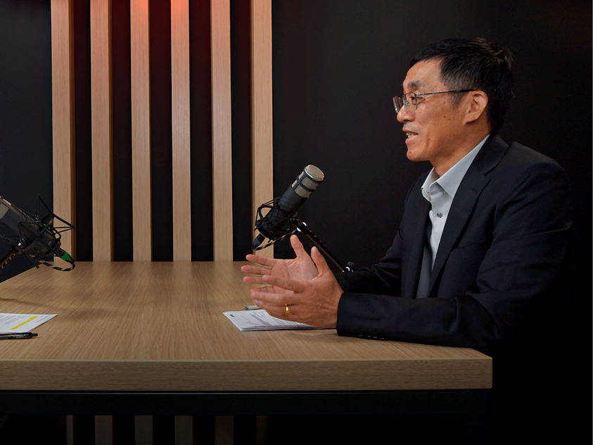 Two individuals discuss industry topics in a formal setting, featuring a Honeywell-branded participant and microphones.
