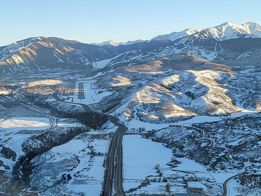 Snow-covered mountain range in Aspen, Colorado, viewed from above, highlighting the landing runway in the foreground