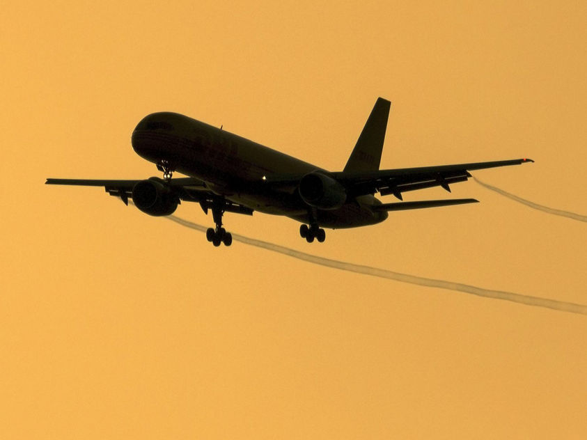 A 757 cleared for landing trailing vapor trails