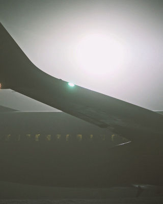 airplane wing on apron covered by dense fog during low visibility procedures at local airport