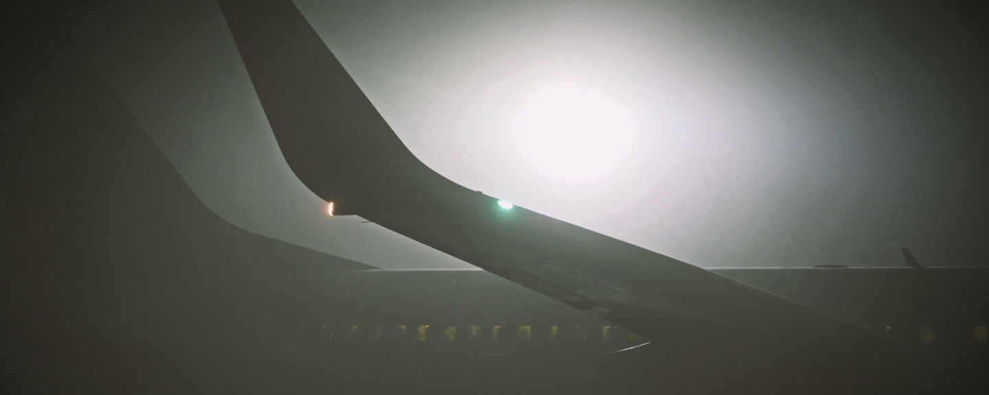 airplane wing on apron covered by dense fog during low visibility procedures at local airport