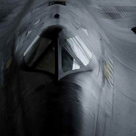 Dramatic frontal view of a military aircraft emphasizing cockpit geometry, metallic surfaces, and stealth-oriented design.