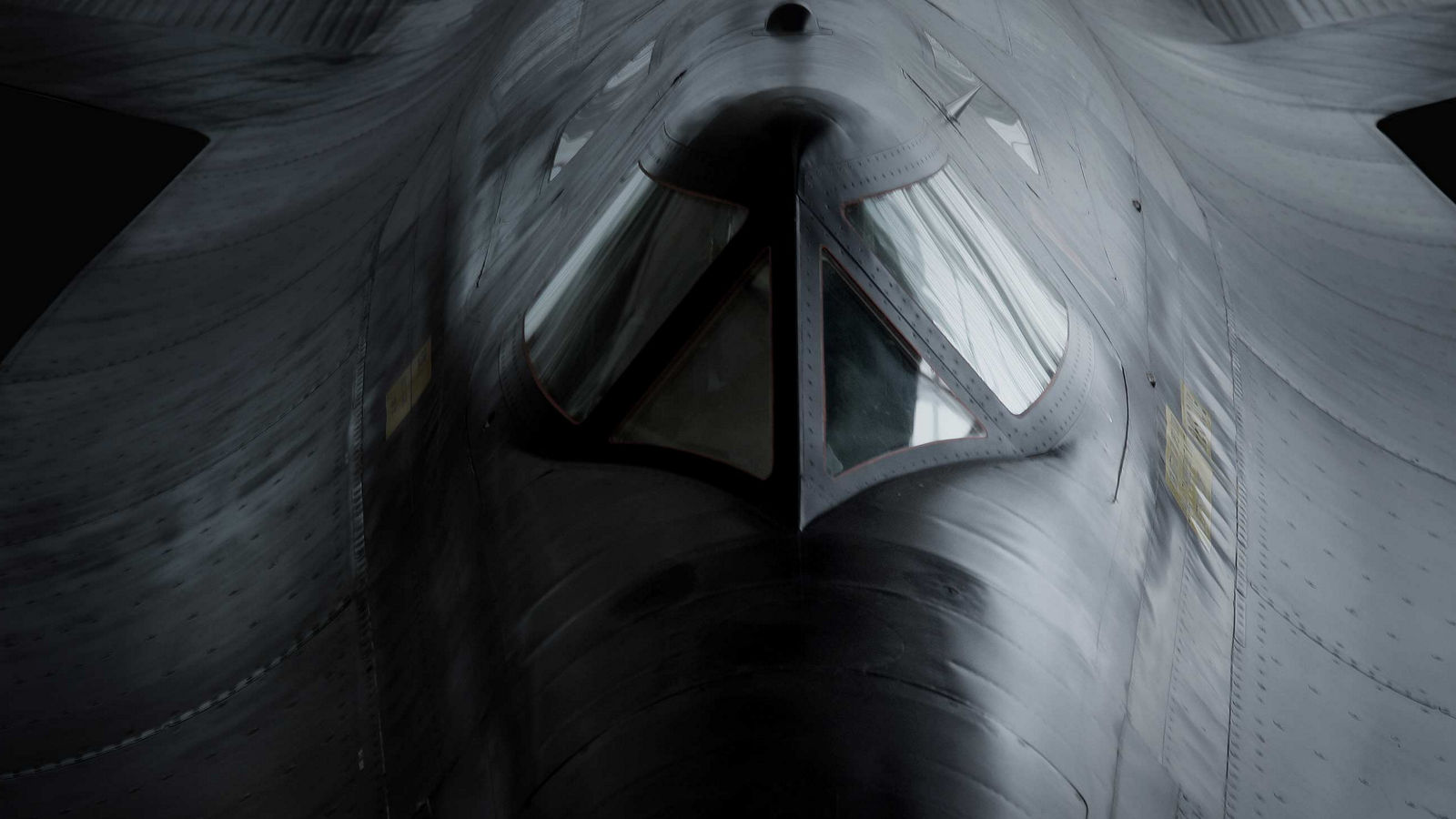 Dramatic frontal view of a military aircraft emphasizing cockpit geometry, metallic surfaces, and stealth-oriented design.