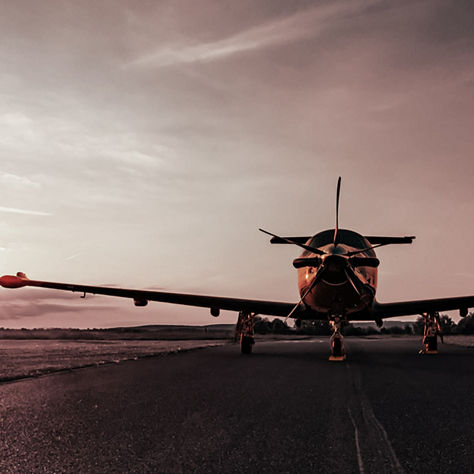 Rear view of parked aircraft on empty runway under warm sky, emphasizing solitude, readiness and evening operations.