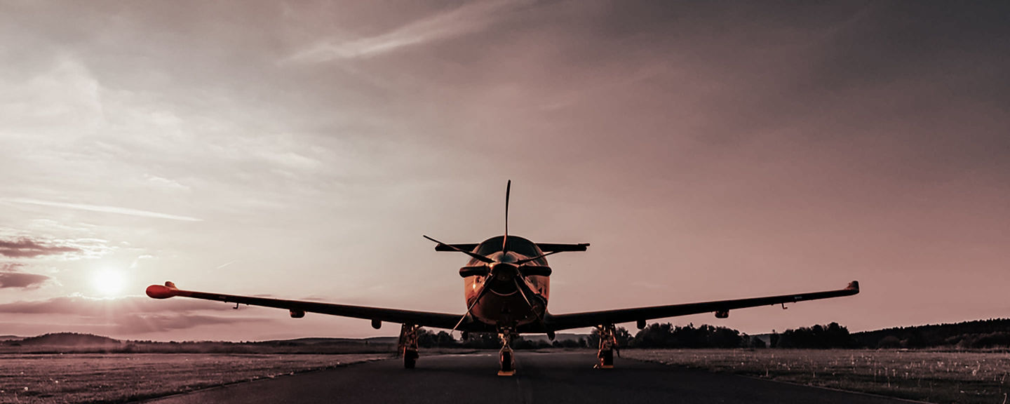Rear view of parked aircraft on empty runway under warm sky, emphasizing solitude, readiness and evening operations.
